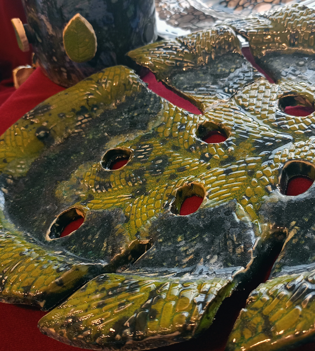 Zbliżenie na pracę ceramiczną - dużego zielonego liścia. Liść ma chropowatą fakturę.