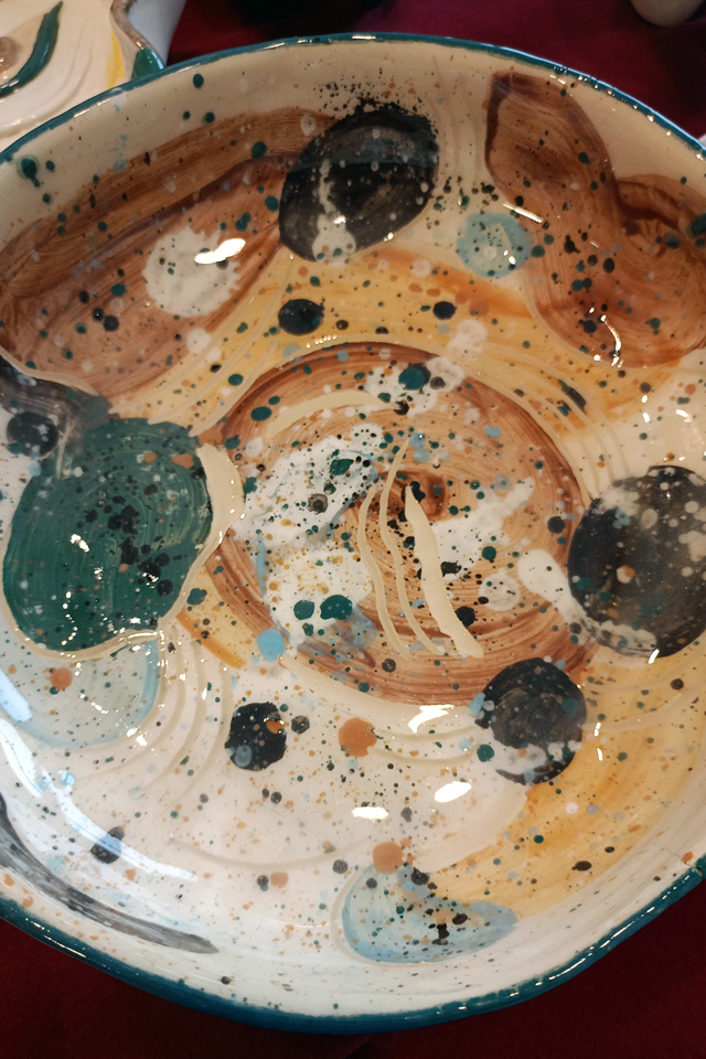 Na zdjęciu wnętrze artystycznej ceramicznej misy. Deseń to nieregularne niebieskie, żółte i białe plamy, przypominające ślady chlapania farbą.