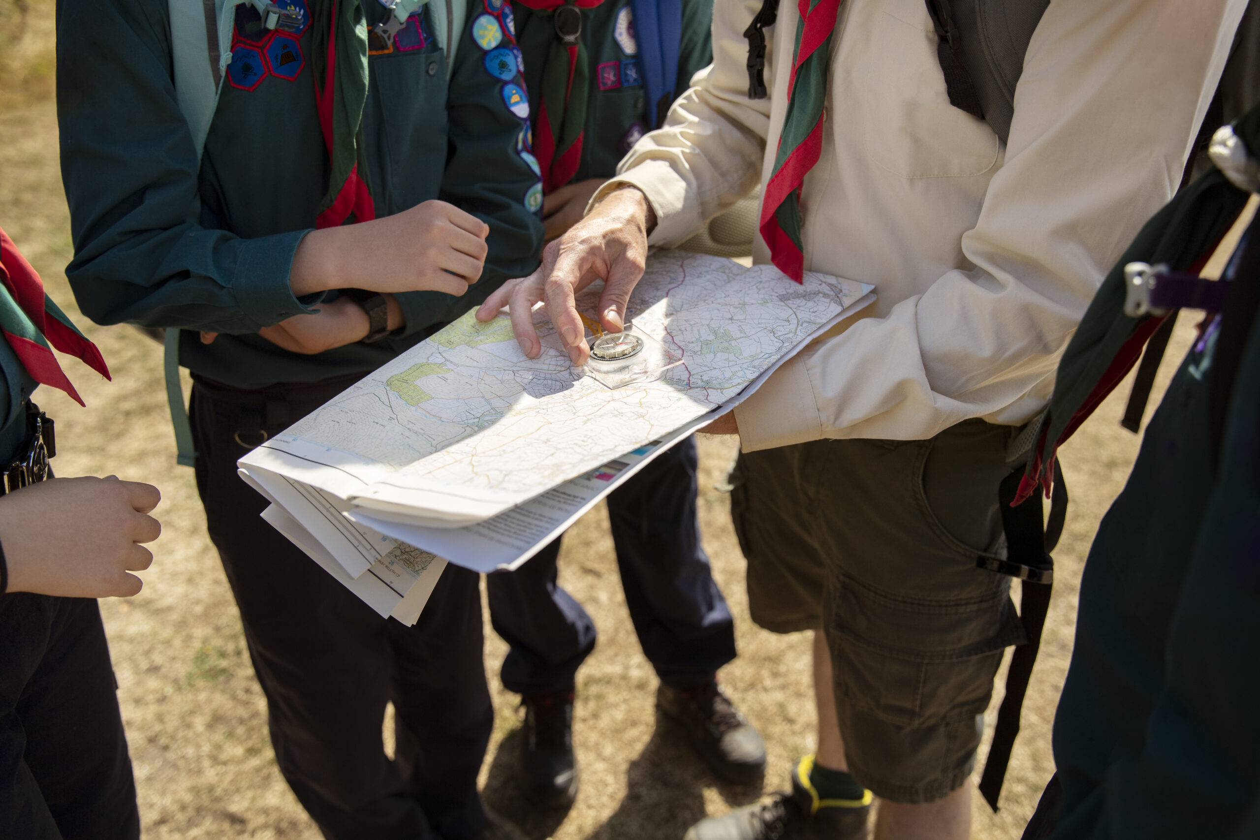 Widok harcerzy trzymających mapę i kompas podczas gry terenowej