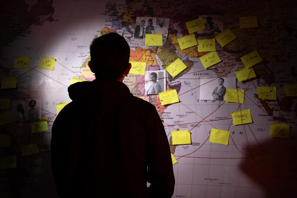 widok sylwetki człowieka z tyłu, stojącego przed mapą z zaznaczonymi punktami poszukiwań