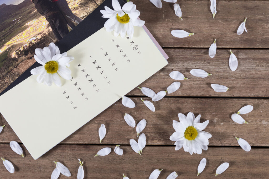 Zdjecie kartki z kalendarza na drewnianym stole w otoczeniu bialych kwiatow