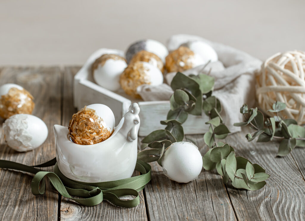 Zdjęcie świątecznych jajek na drewnianym stole w towarzystwie bukszpanu