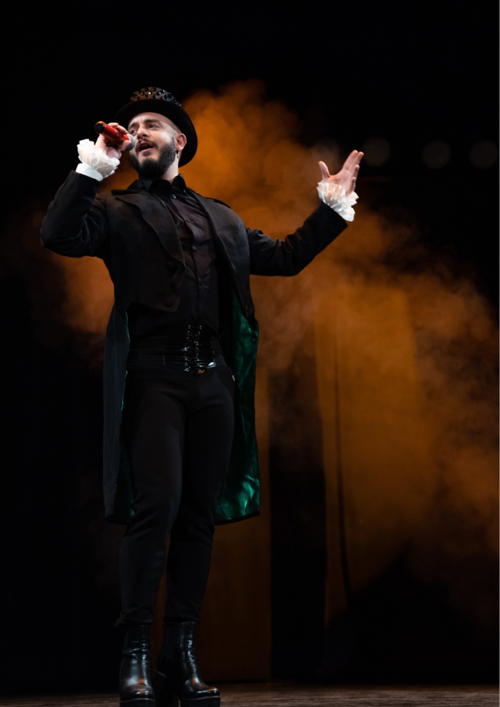 Zdjęcie artysty Dawida Bawora w czarnym smokingu i cylindrze śpiewającego do mikrofonu