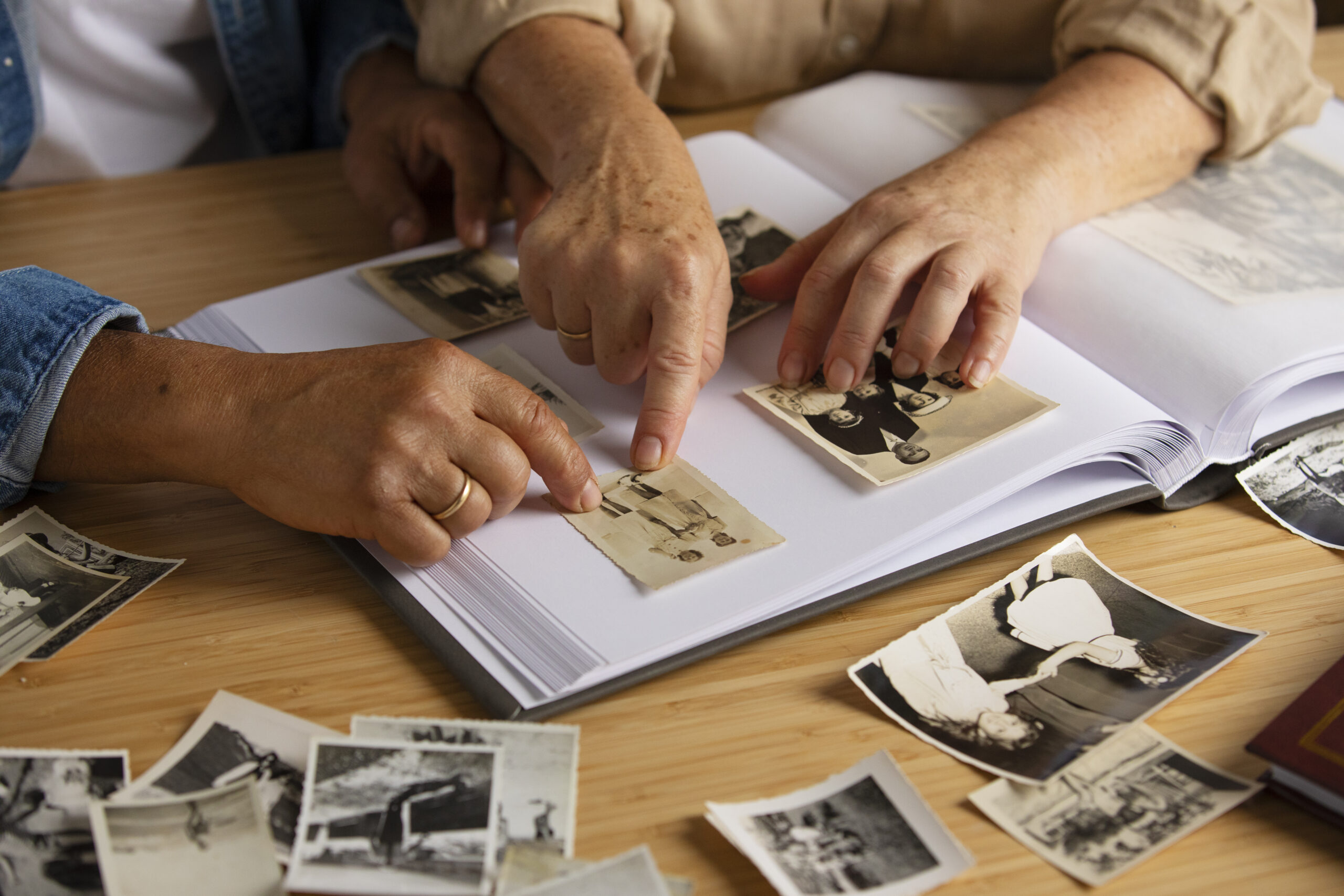 Zbliżenie na ręcę kobiety i mężczyzny, układających stare zdjęcia w albumie
