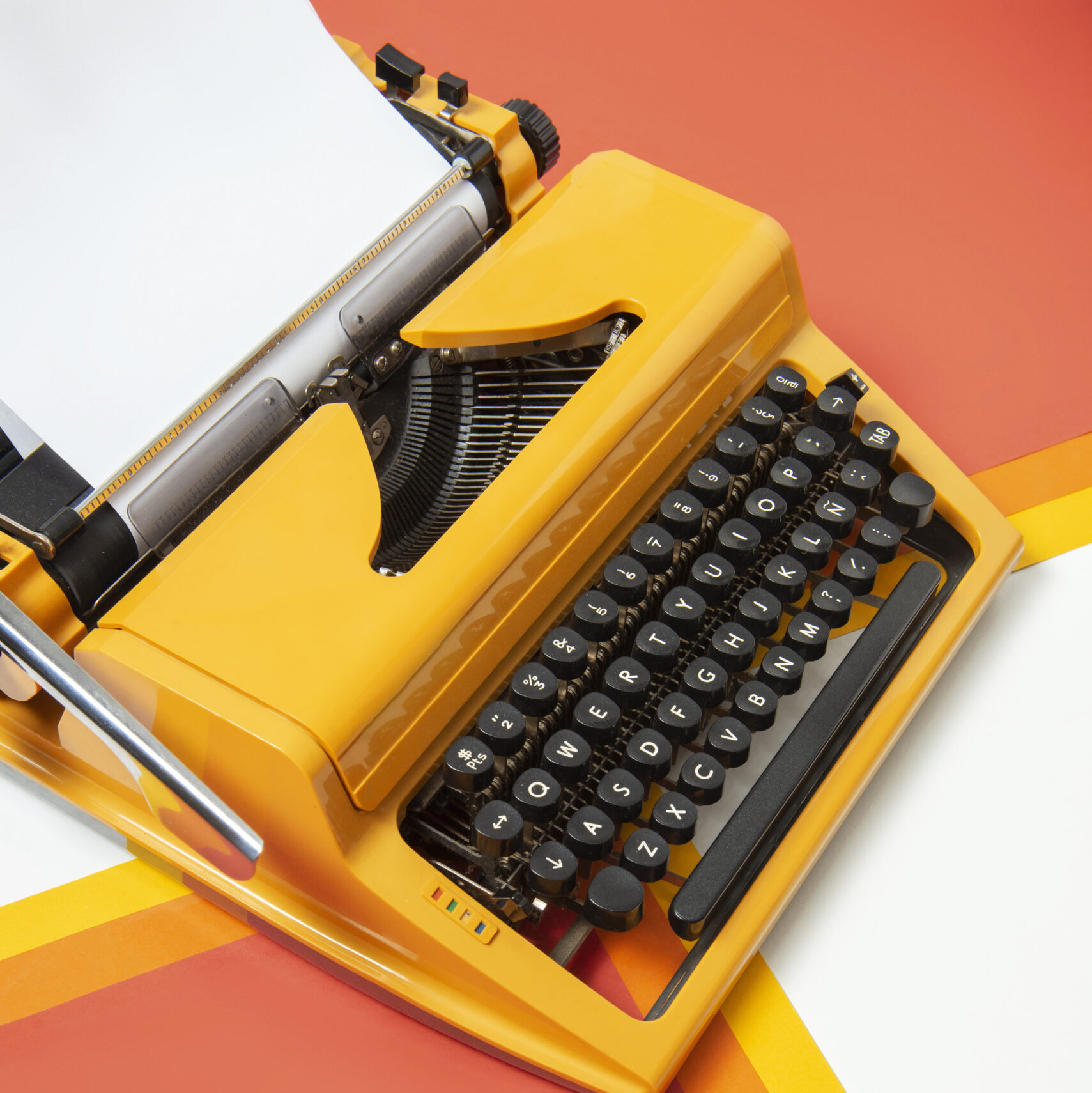 zdjęcie żółtej maszyny do pisania na pomarańczowo-białym tle