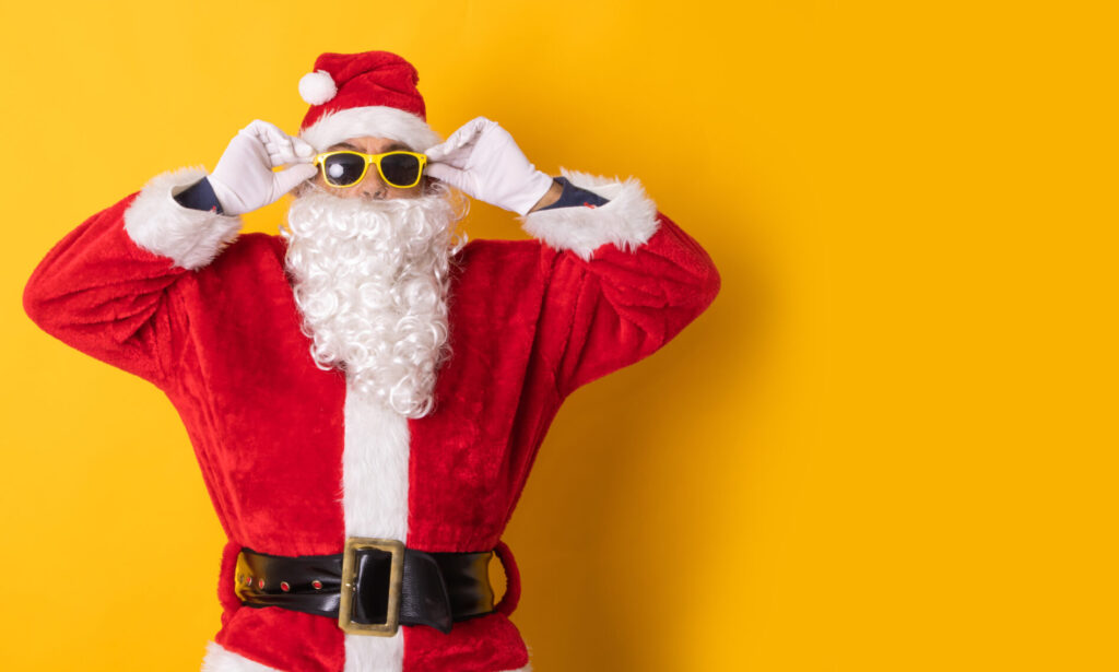 Na żółtym tle postać Świętego Mikołaja: ubrany jest w czerwony strój obszyty białym futerkiem, na głowie ma czerwoną czapę, przepasany jest grubym pasem z dużą klamrą. Ma długą białą brodę, wąsy, a dłońmi w białych rękawicach zakłada na oczy okulary w żółtych grubych oprawkach.